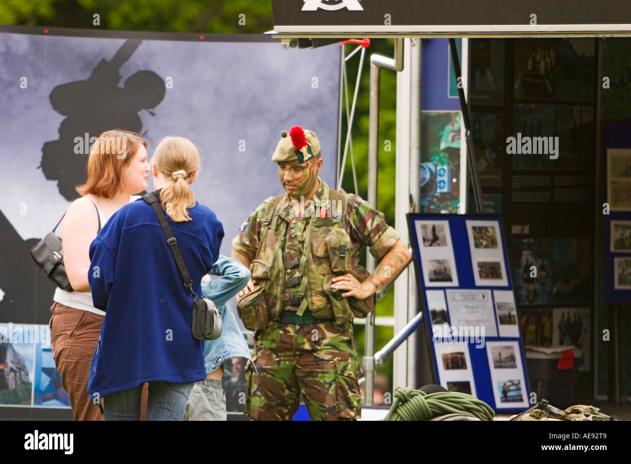 Soldat d'infanterie dans la peinture de camouflage parle aux gens au stand de l'armée de terre recruiment Banque D'Images