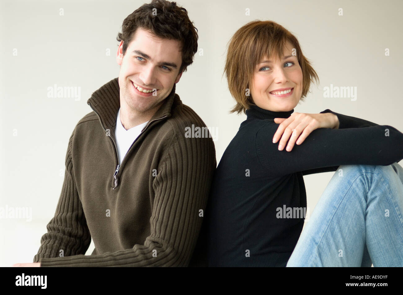 Smiling couple assis dos à dos Banque D'Images