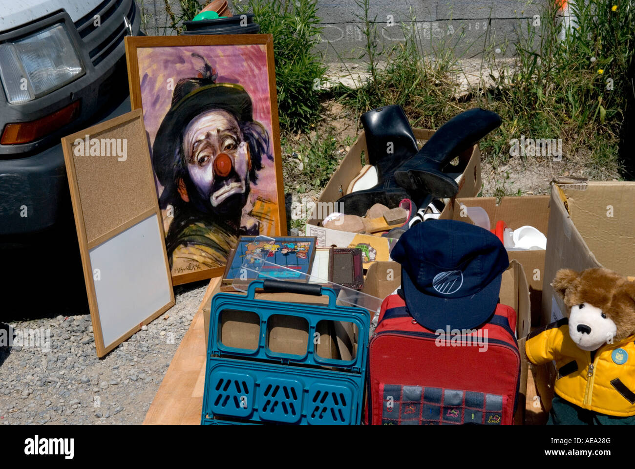 Une peinture kitsch d'un clown triste à la recherche se trouve parmi un tas d'ordure dans un marché aux puces français Banque D'Images