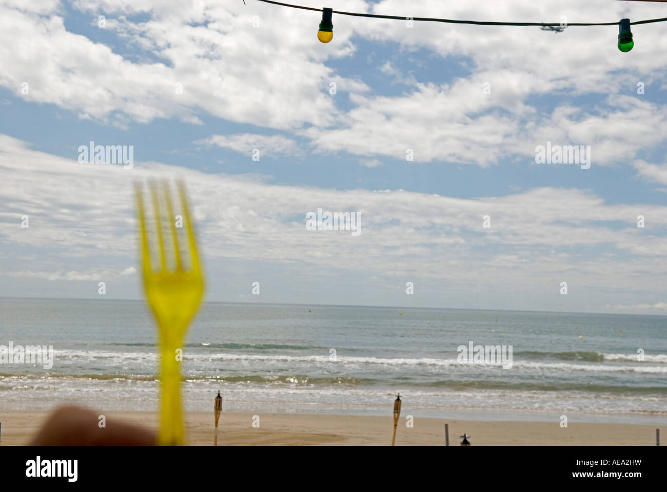 Un détail d'une fourche jaune fermer jusqu'à un bar de plage avec la plage et la mer en arrière-plan Banque D'Images