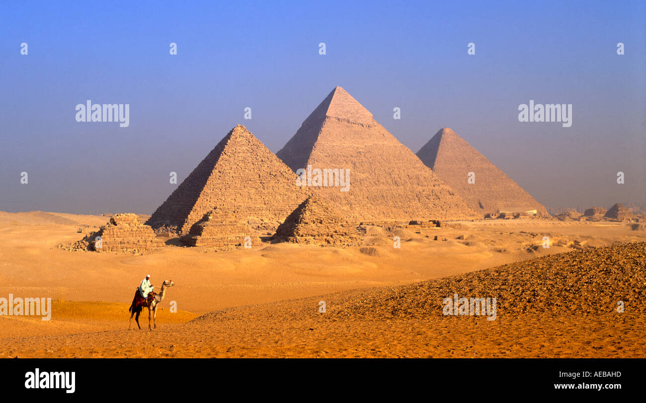 Pyramides et tribu bédouine au lever du soleil à dos de chameau, Giza, Le Caire, Egypte Banque D'Images