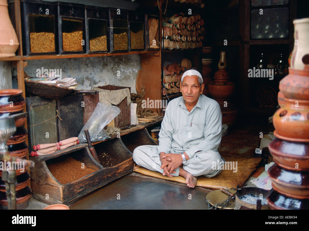 Commerçant sitting cross legged dans son magasin la vente de tabac Islamabad au Pakistan Banque D'Images