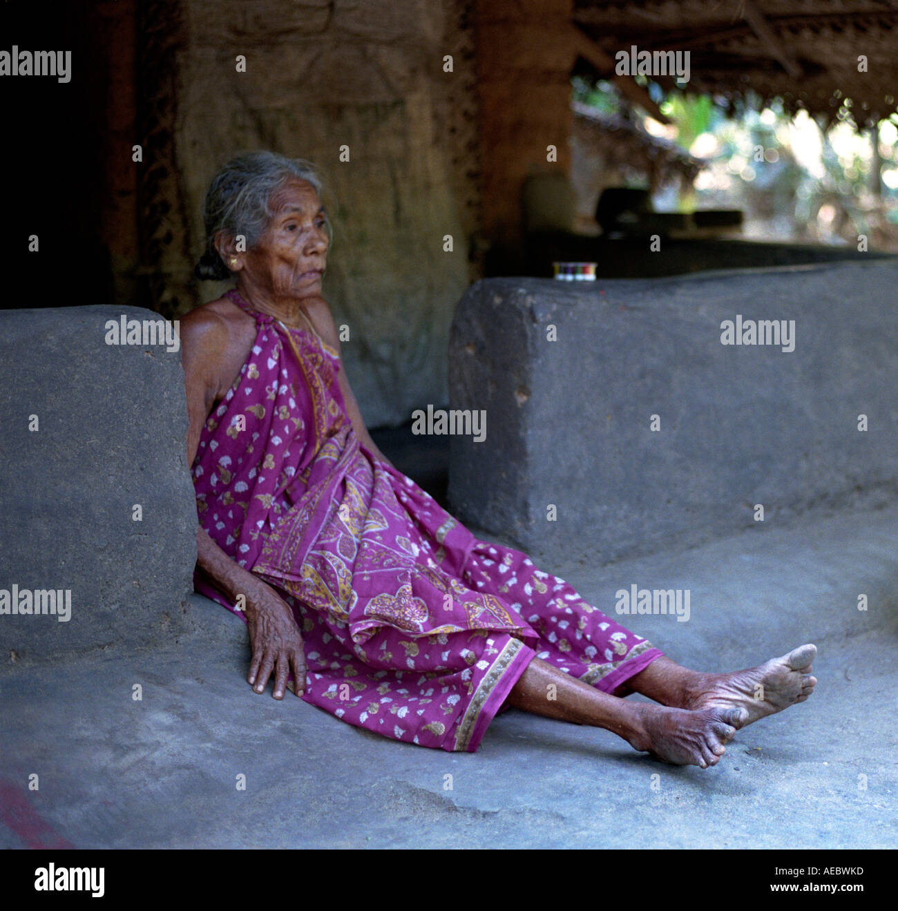 Une vieille femme assise tribale en face de sa hutte, Kerala, Inde Banque D'Images