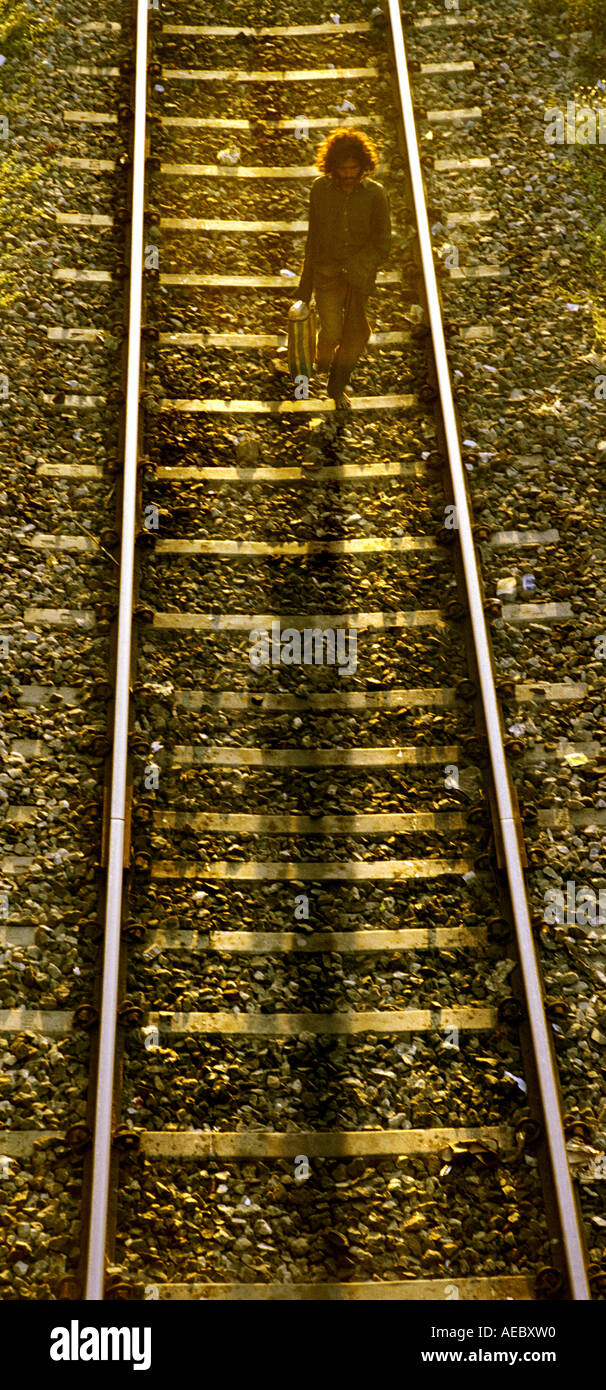 Un voyageur solitaire, mendiant, marchant le long d'une voie ferrée dans la lumière du soir. Bird's eye view shot Banque D'Images