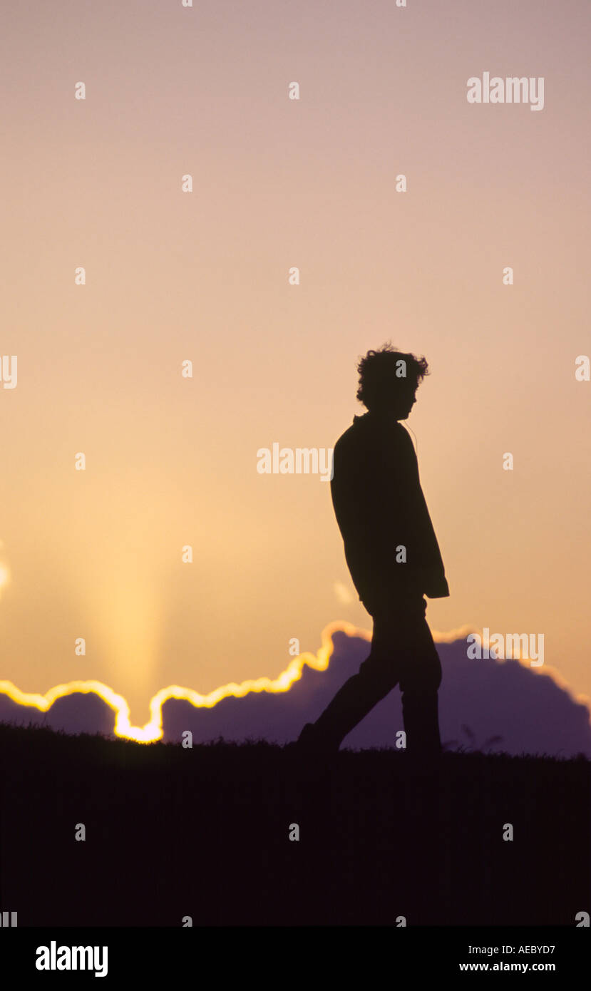 La silhouette d'une figure promenades le long du sommet d'une colline avec un coucher de soleil spectaculaire à l'arrière-plan Primrose Hill London Banque D'Images