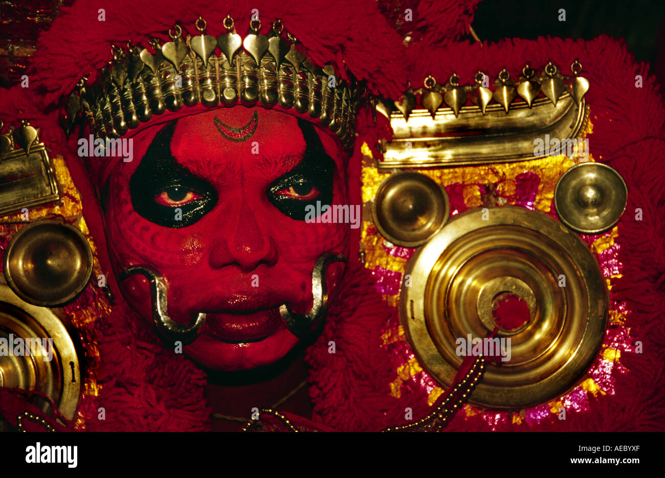 Gros plan d'une face avec l'artiste Theyyam forme traditionnelle de rouge foncé. Banque D'Images