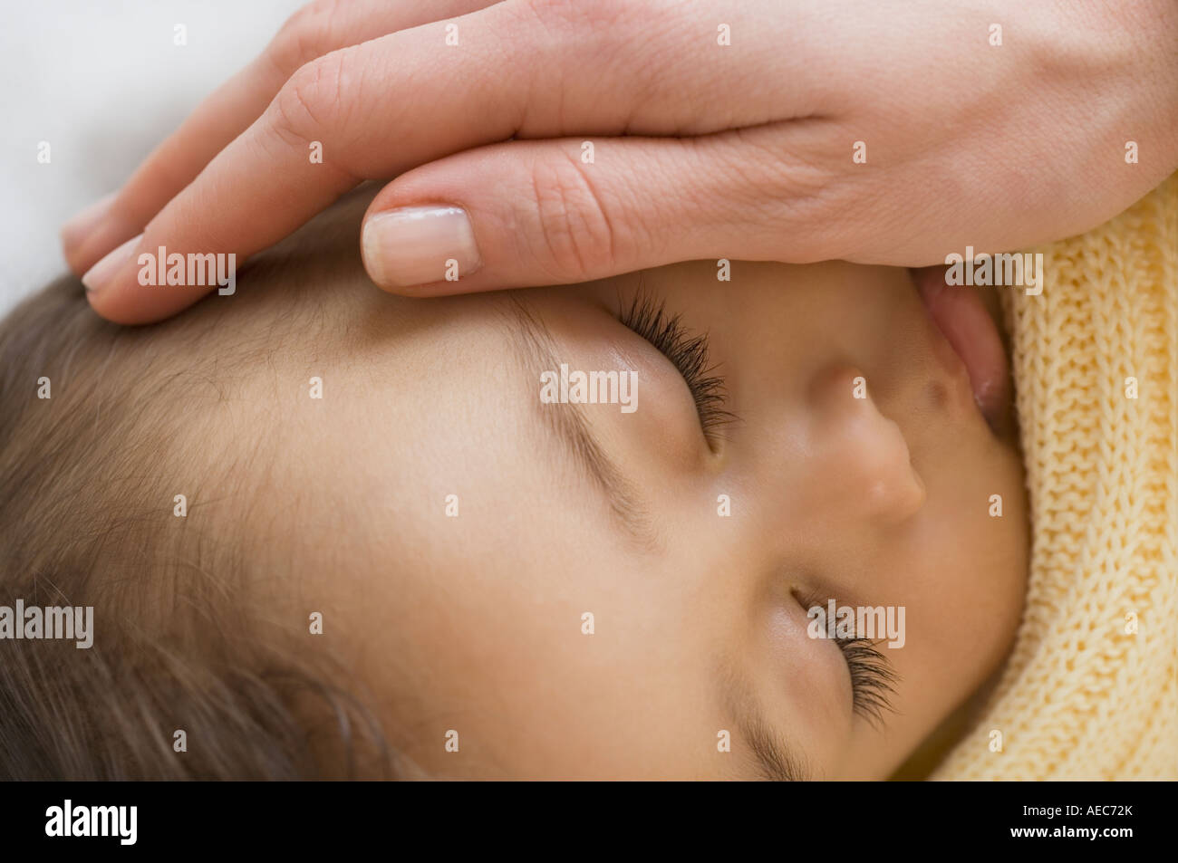 Close up of Hispanic bébé endormi avec la main sur la joue de la mère Banque D'Images