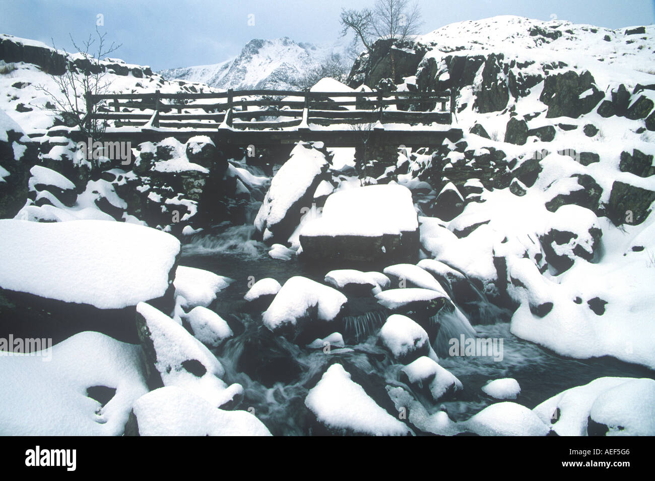 Pont de bois sur Ruisseau de montagne en hiver neige Cwm Idwal le Snowdonia au nord ouest du pays de Galles Banque D'Images