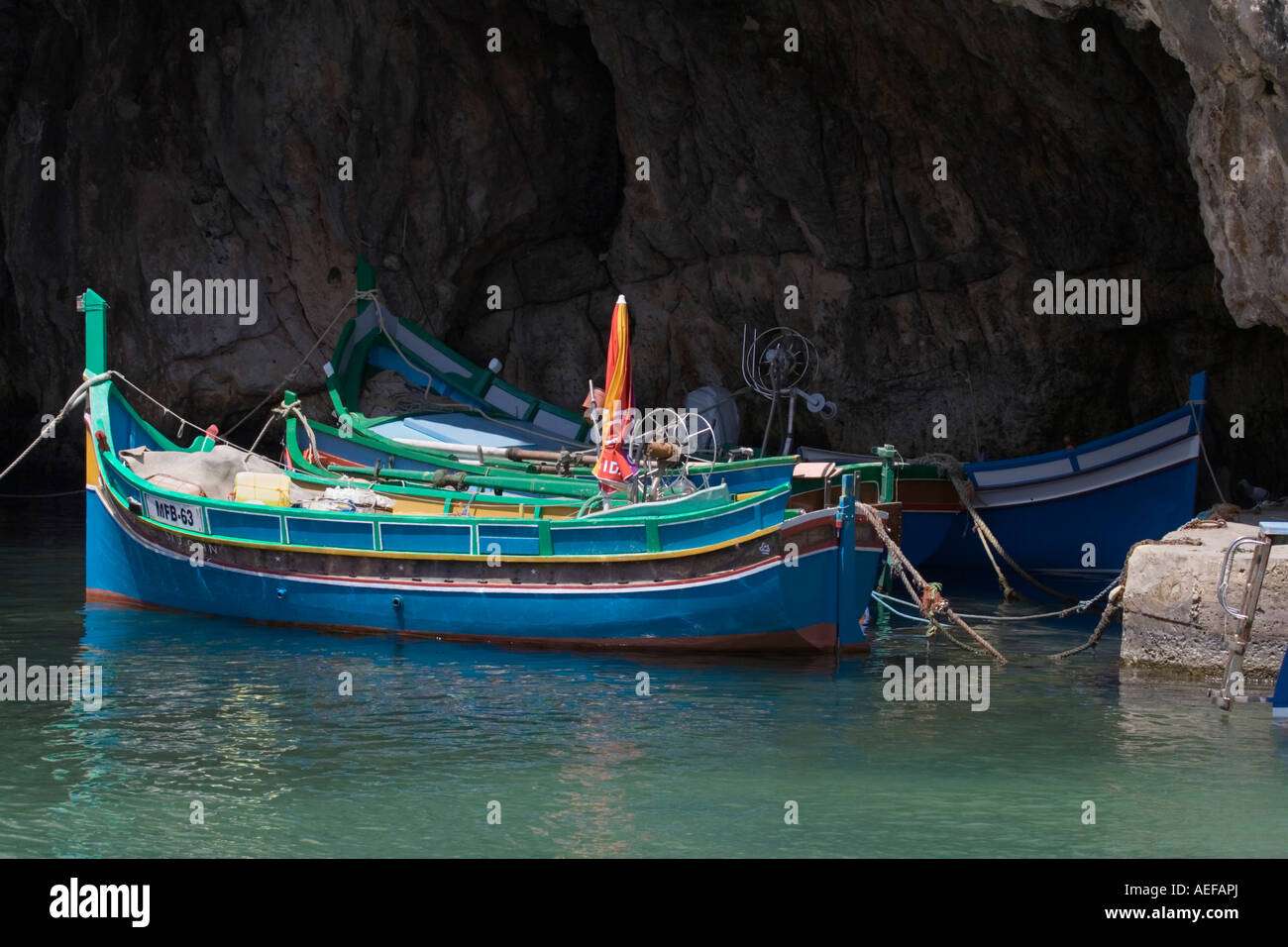 Bateaux de pêche maltais du type luzzu amarrés dans une caverne à Xlendi, Gozo, Malte Banque D'Images