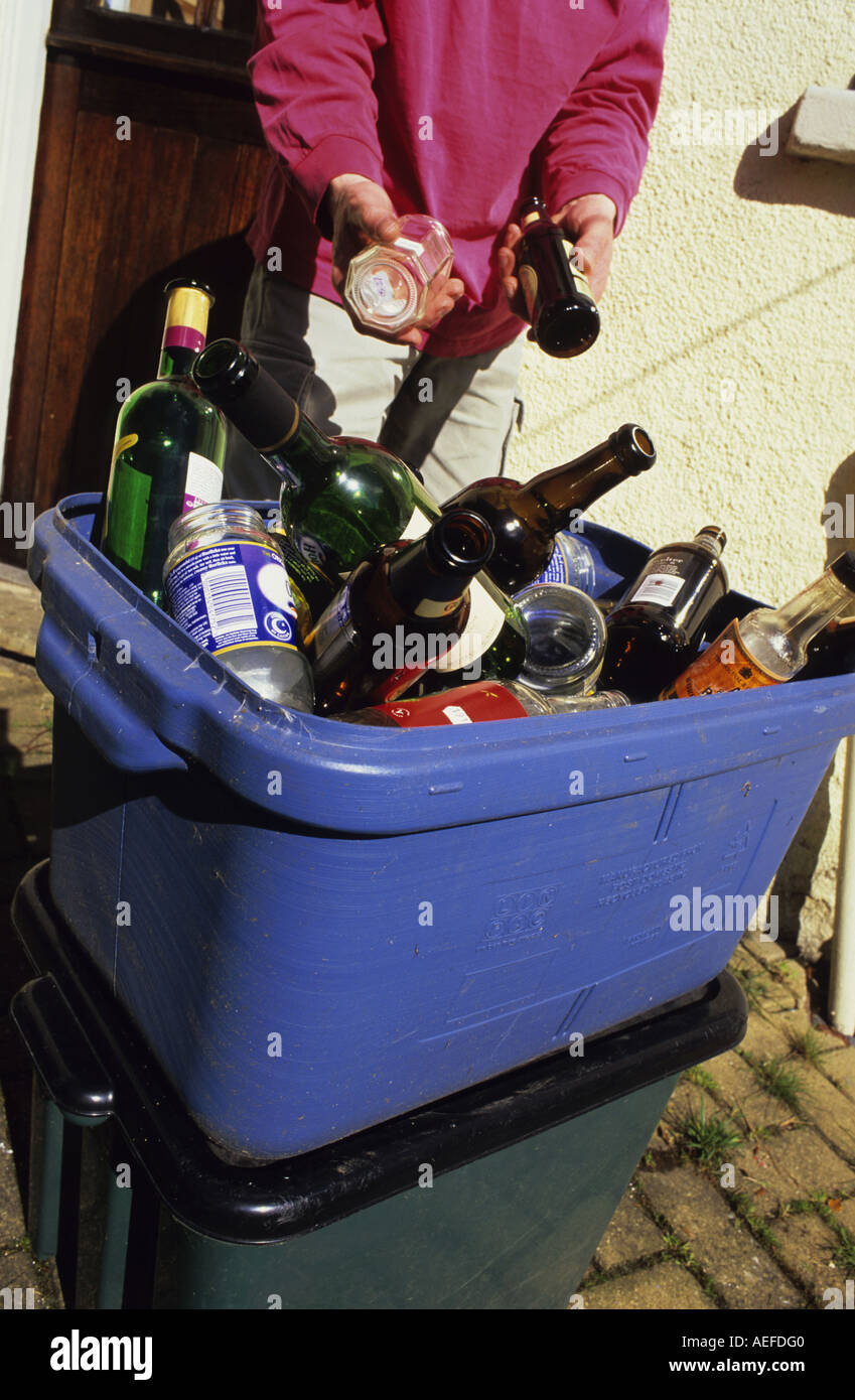 Mettre des bouteilles en verre en porte conteneurs de recyclage à l'extérieur de la maison Banque D'Images