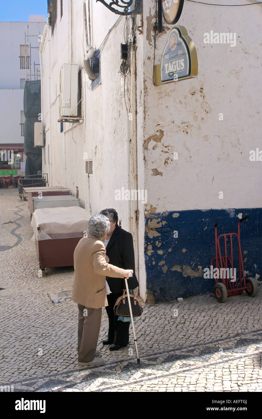 Deux vieilles personnes âgées portuguise femmes parlant dans la rue à côté d'un bâtiment blanc, à Albufeira. Banque D'Images