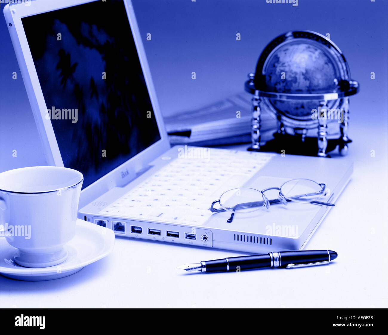 Ordinateur portable bureau globe lunettes stylo tasse soucoupe journal bleuâtre de la tâche de travail ordinateur technologie concept d'affaires Banque D'Images