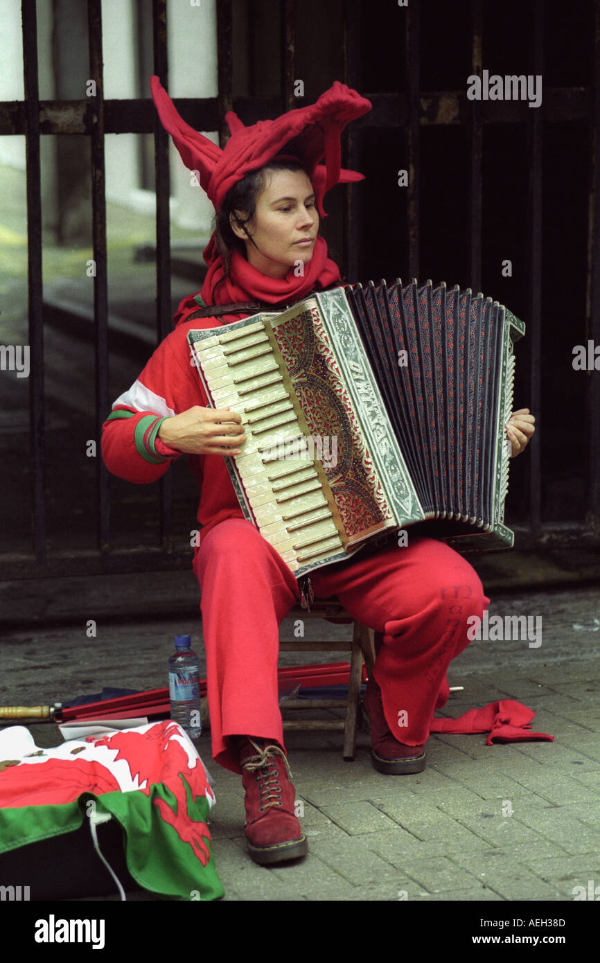 Joueur d'Accordéon musicien ambulant dans un costume de dragon rouge dans les rues de Cardiff au Pays de Galles avant un match de rugby international UK Banque D'Images