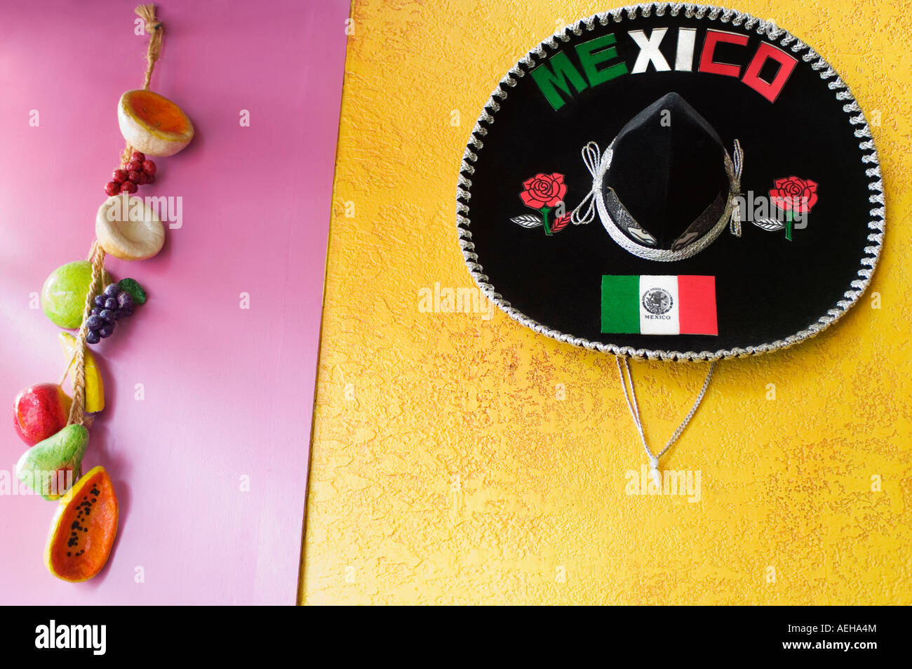 Un sombrero mexicain et les fruits et légumes en papier mâché accrocher sur des murs peints de couleurs vives. Banque D'Images