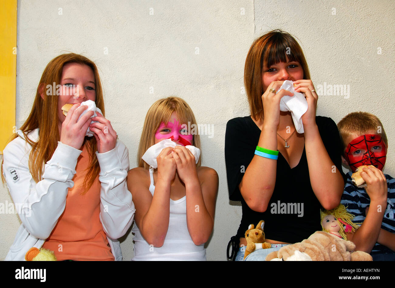 Quatre jeunes manger malbouffe lors d'une journée en famille Middlesex UK Banque D'Images