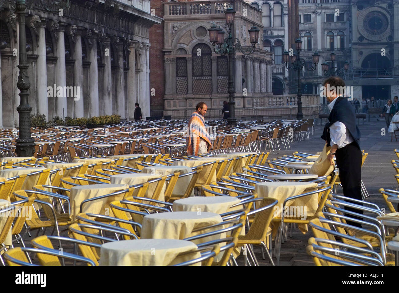 Homeless man walking passé cafe tables dans S Marco, Venise Italie, tôt le matin. Banque D'Images