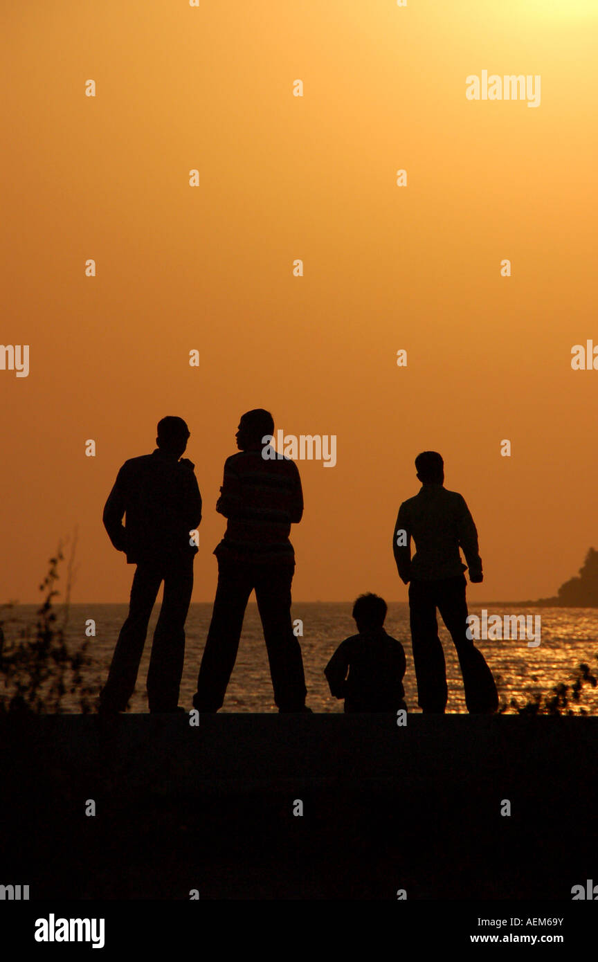 Quatre amis sur le mur de la mer au coucher du soleil à Mumbai, Inde Banque D'Images