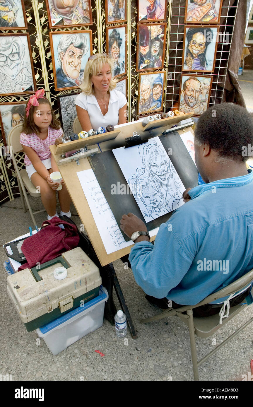 Artiste de la rue de sexe masculin dessine une caricature d'une mère et fille Banque D'Images