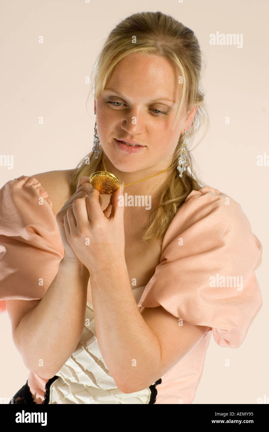 Blonde femme irlandaise en costume victorien vintage à la recherche d'un médaillon d'or Banque D'Images