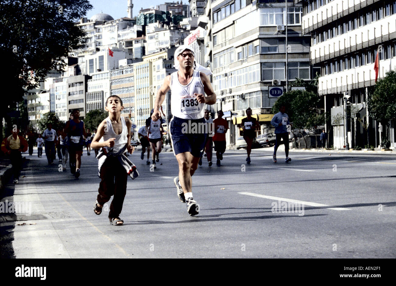 Garçon courir officieusement au Marathon d'Istanbul, portant des sandales avec un coureur adulte à ses côtés Banque D'Images