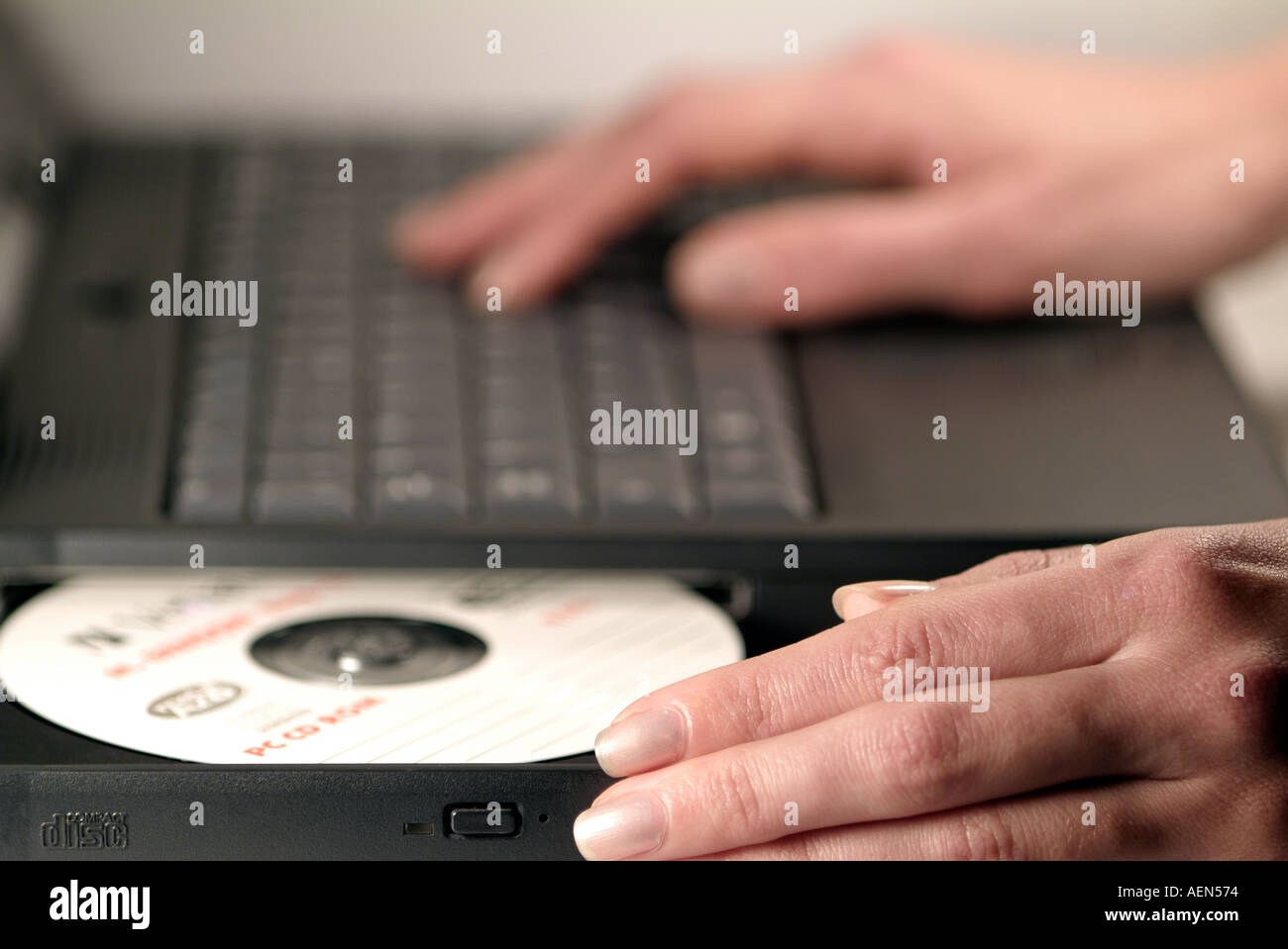 Femme d'insérer un disque dans le lecteur de CD-Rom d'un ordinateur portable Banque D'Images
