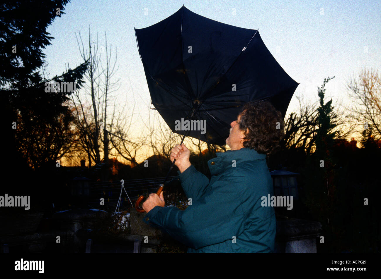 Homme avec parapluie souffler à l'intérieur dehors sur Jour de vent Banque D'Images