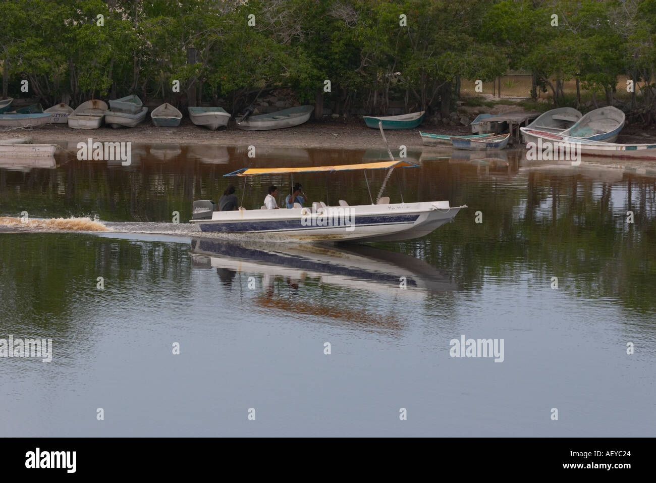 Petit bateau avec 4 personnes sur les voies navigables Celestan Yucatan Mexique avec des bateaux sur la rive Banque D'Images