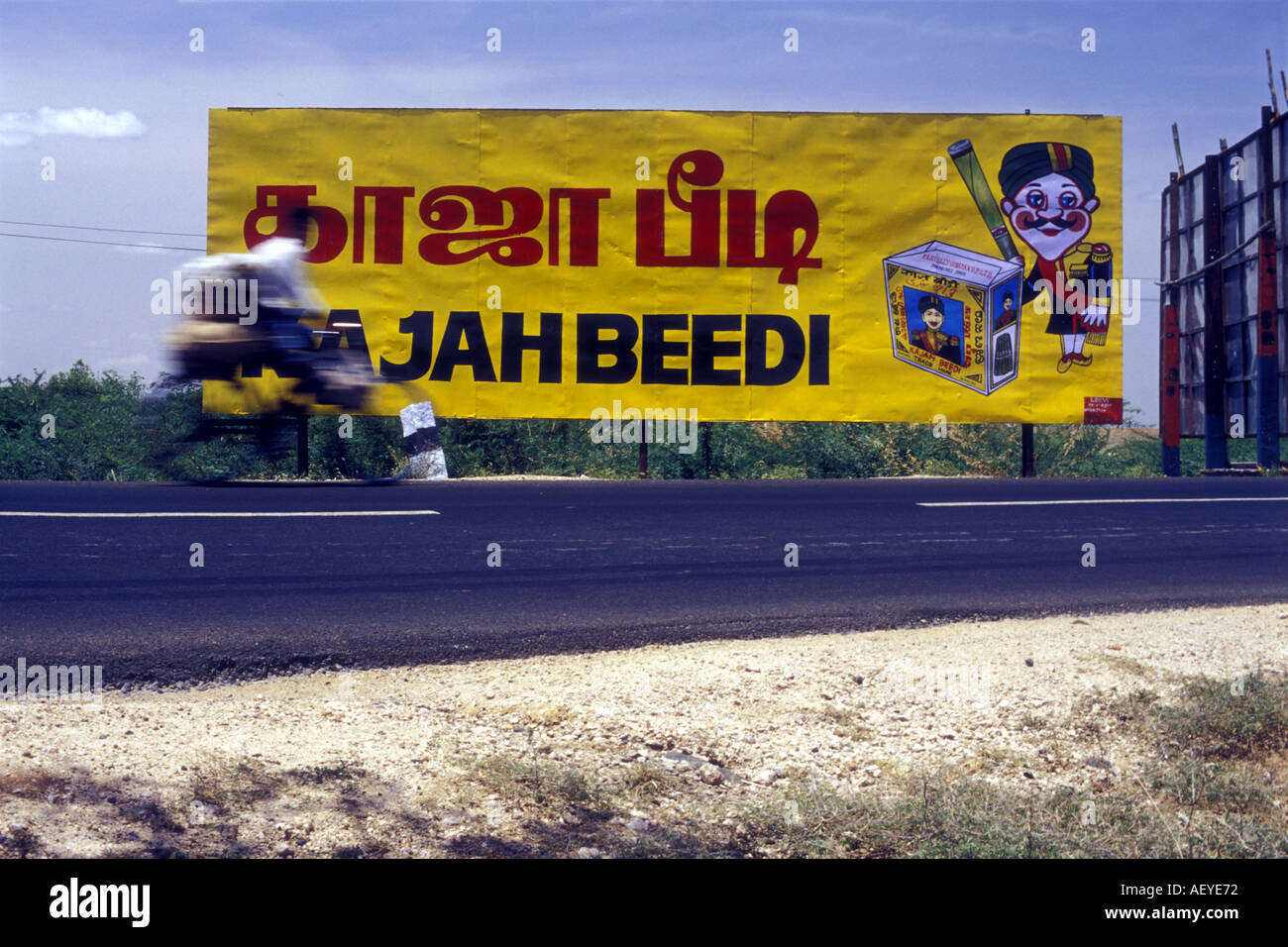 Un cycliste a passé les vitesses des panneaux publicitaires en bordure des cigarettes au Tamil Nadu Inde Photo par Andrew Hasson 2002 Banque D'Images