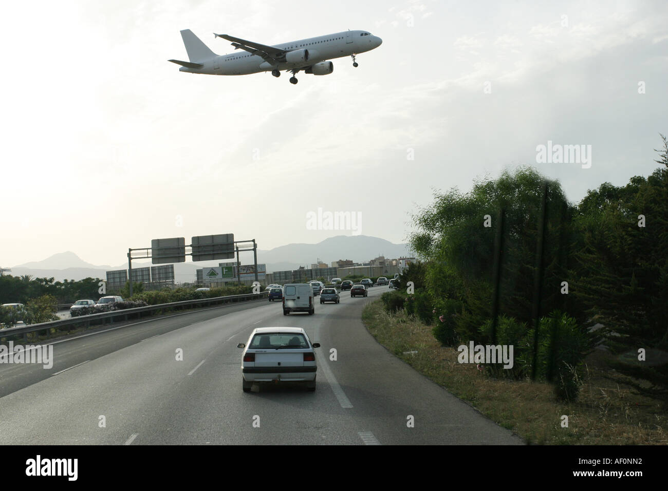 Conduire sur l'autoroute près de l'aéroport de Palma de Majorque en Espagne. Un avion est en train de traverser le trafic et est sur le point d'atterrir. Banque D'Images