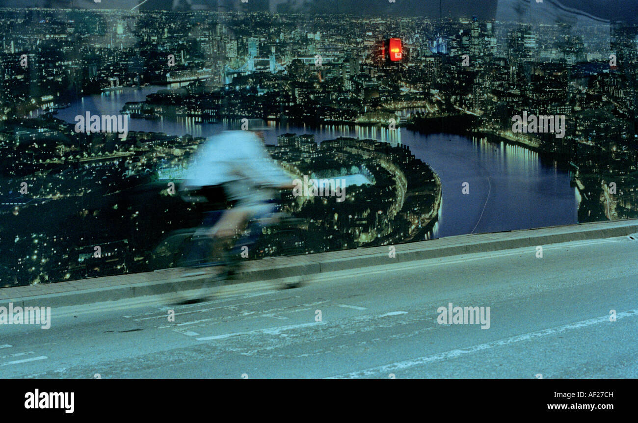 Circonscription cycliste passé une grande photographie de Londres à côté de l'emplacement de l'édifice, à l'Est de Londres. Banque D'Images