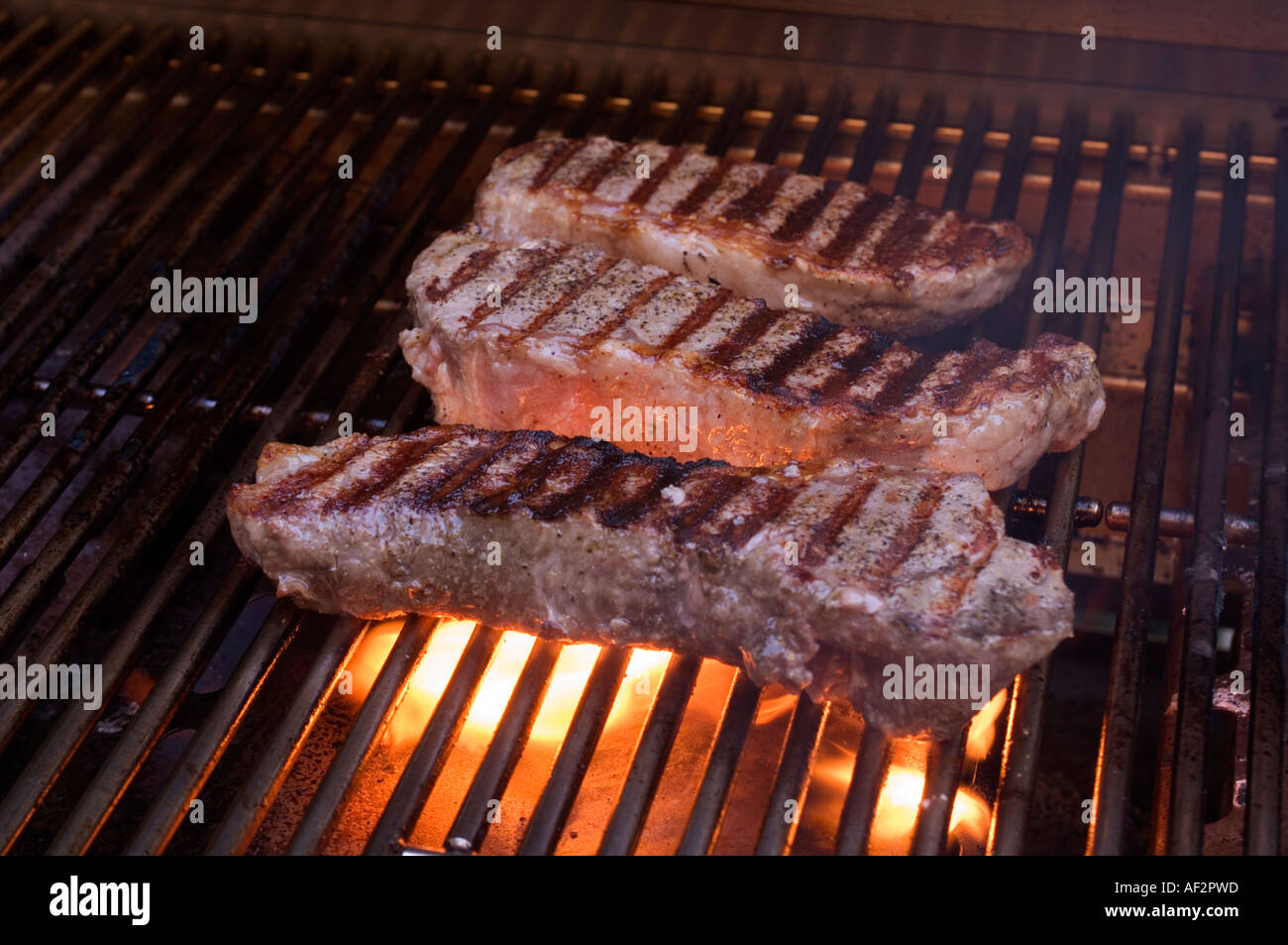 New York trois steaks grillés sur un barbecue au gaz Banque D'Images