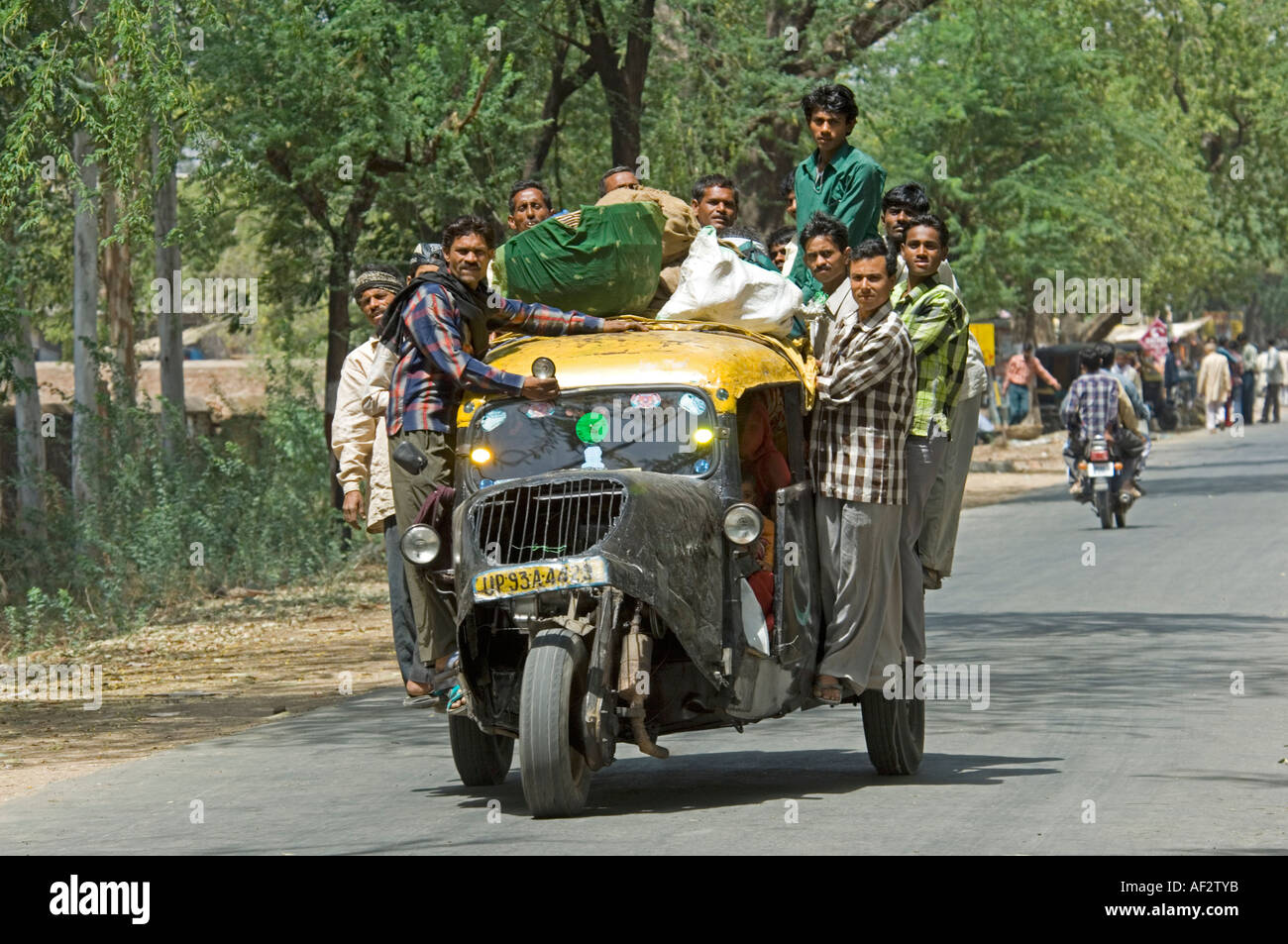 Un pousse-pousse à trois roues pleine à craquer avec les habitants accroché sur tous les disques durs autour de comme il le long d'une route. Banque D'Images