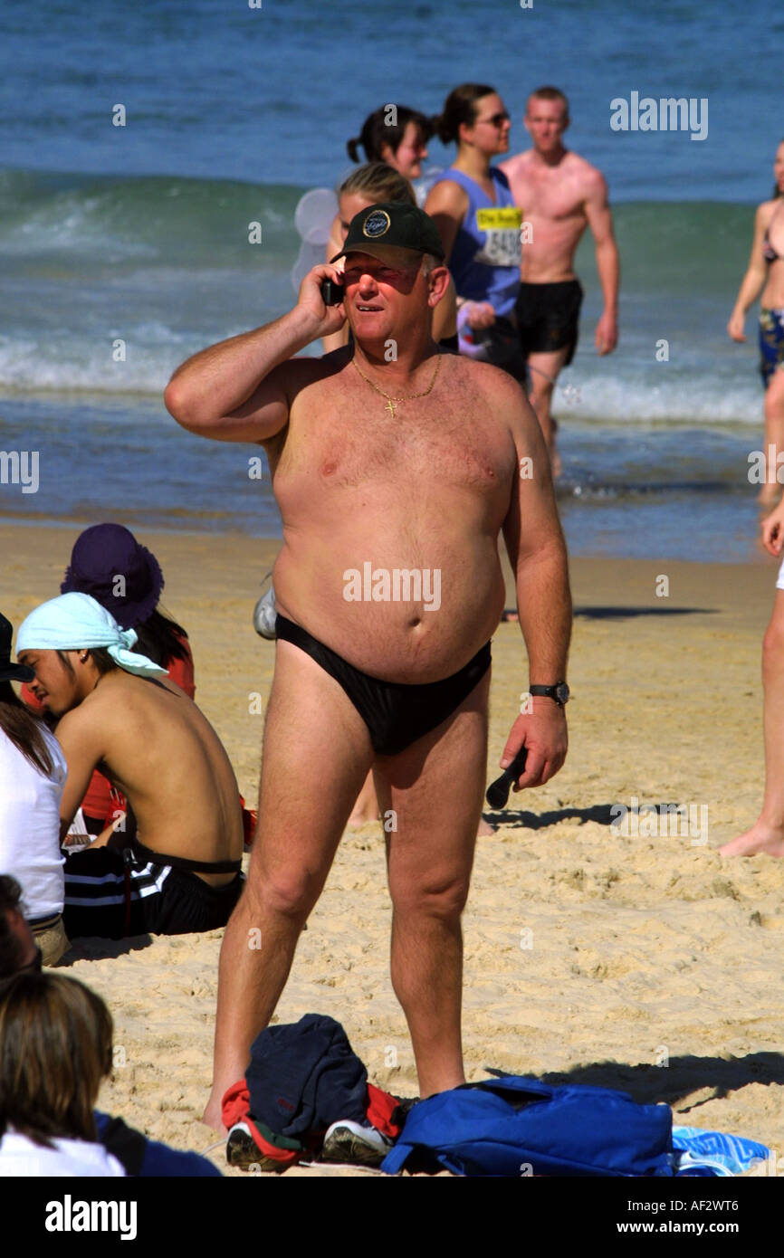 Un homme utilise un téléphone mobile ou téléphone cellulaire pour communiquer sur la plage de Bondi Sydney Australie Banque D'Images