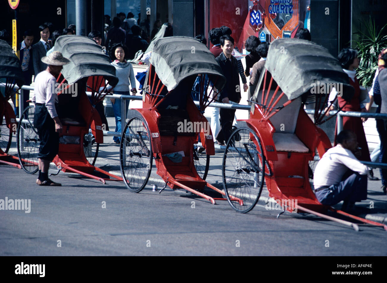 3 pousse-pousse typique en rouge avec auvent blanc couvre les conducteurs dans la fin des années 1970, l'attente pour les clients à Kowloon Hong Kong Banque D'Images