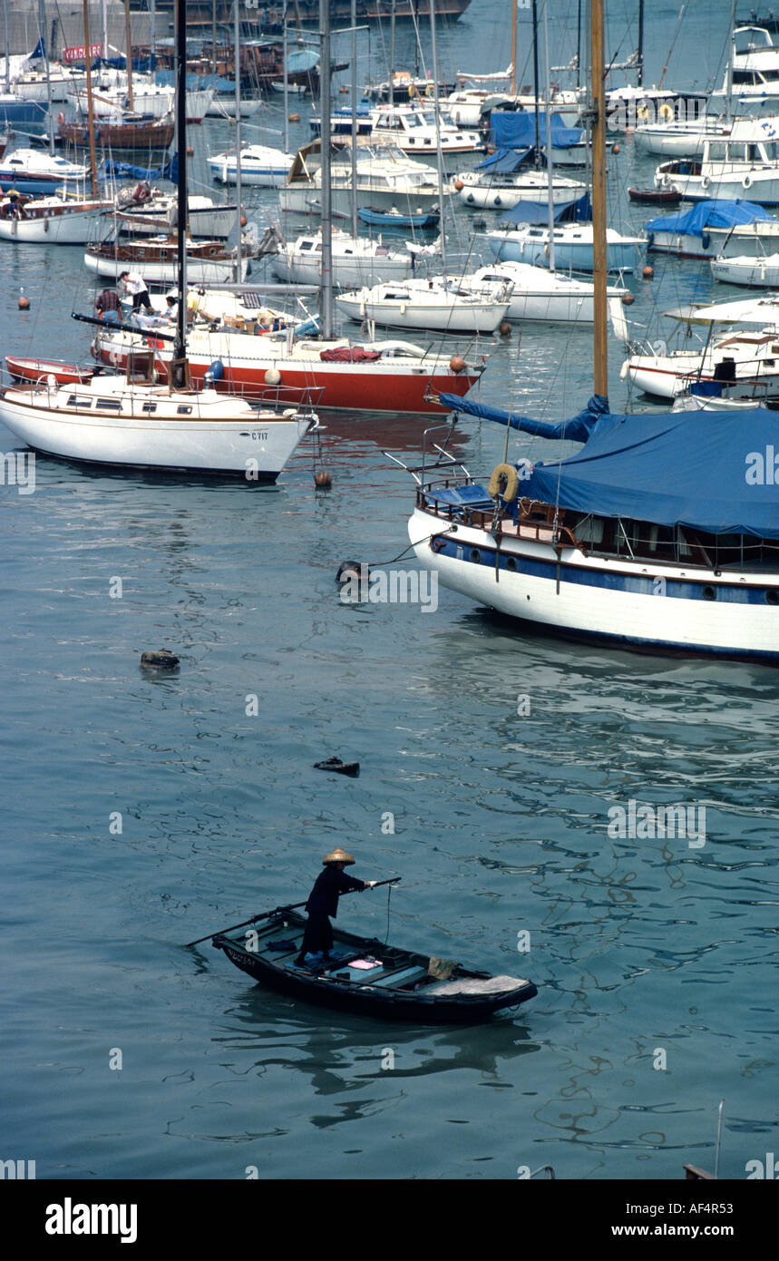 Taxi d'eau traditionnels déménagement par stern paddle sur fond de yachts de luxe à Causeway Bay Hong Kong Chine refuge typhon Banque D'Images