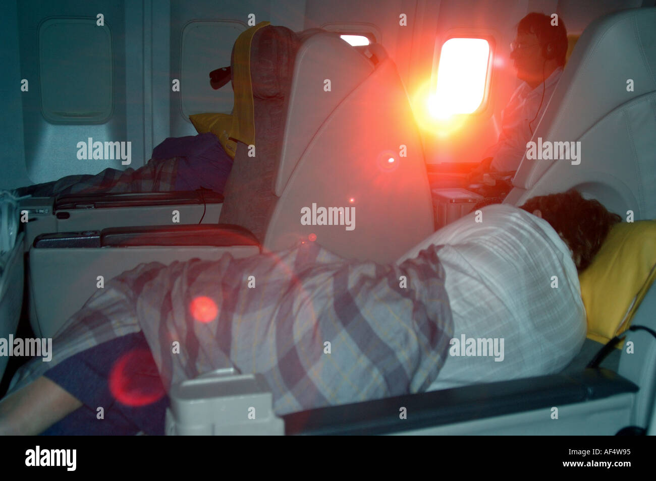 Assurances passagers dormant dans un Royal Brunei Airlines double classe affaires comme le soleil perce la cabine windo Banque D'Images