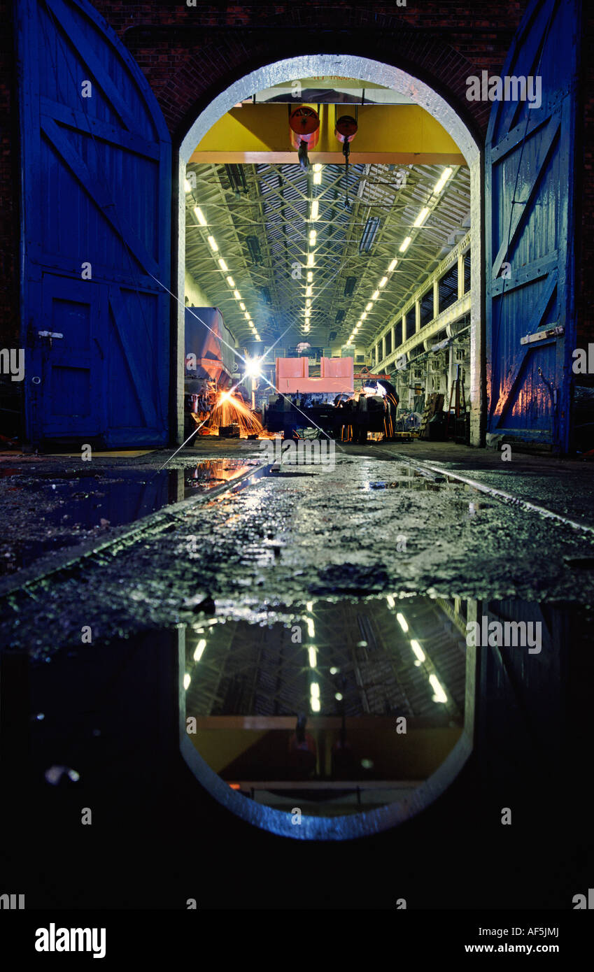 Soudeur travaille dans la nuit dans l'atelier d'ingénierie des travaux de réparation d'un wagon de chemin de fer Banque D'Images