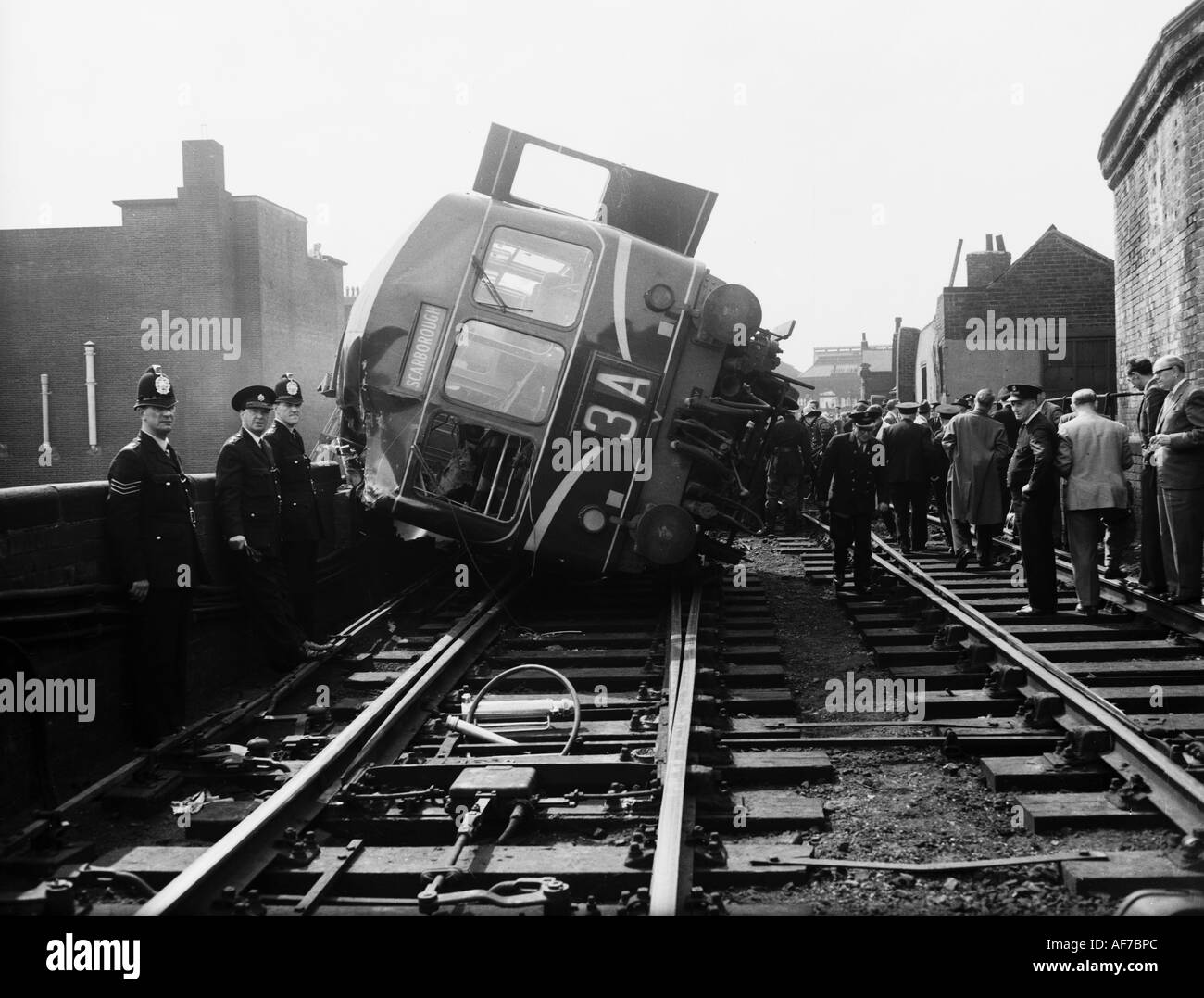 Vintage photographie en noir et blanc d'une foule de personnes y compris l'affichage de la police de locomotive a déraillé sur le côté incliné. Banque D'Images