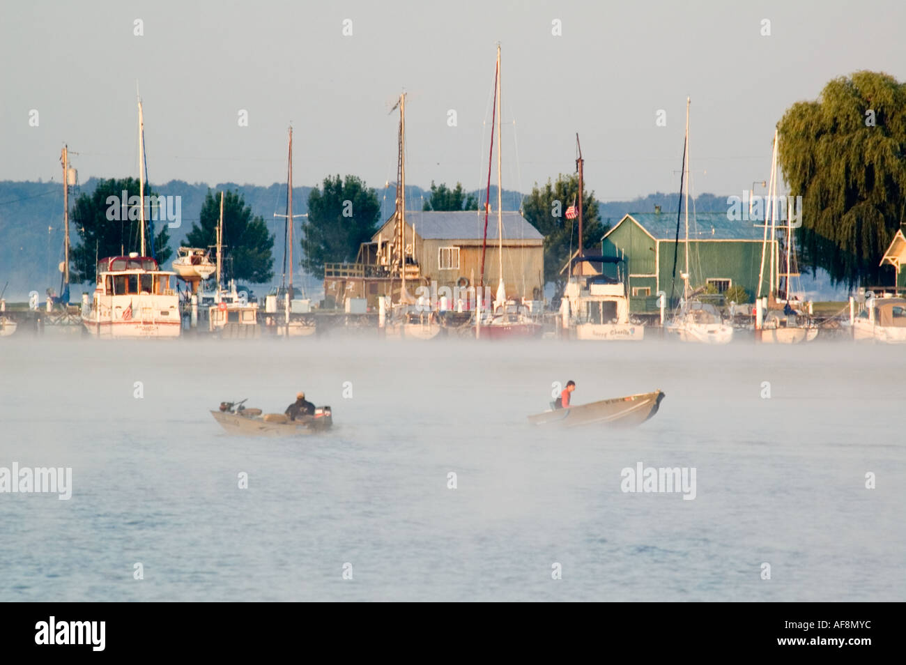 Deux petits bateaux de pêche passent devant une marina sur le Lac Blanc près de Montague MI Banque D'Images