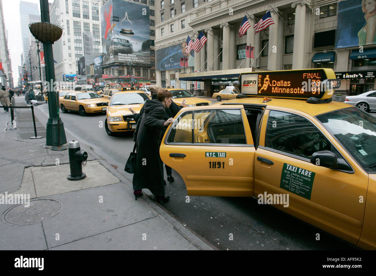 Les passagers blancs d'âge moyen sortent de la porte arrière de la cabine jaune à la station de taxis sur la 7ème Avenue à l'extérieur du Madison Square Garden New york City usa le jour froid Banque D'Images