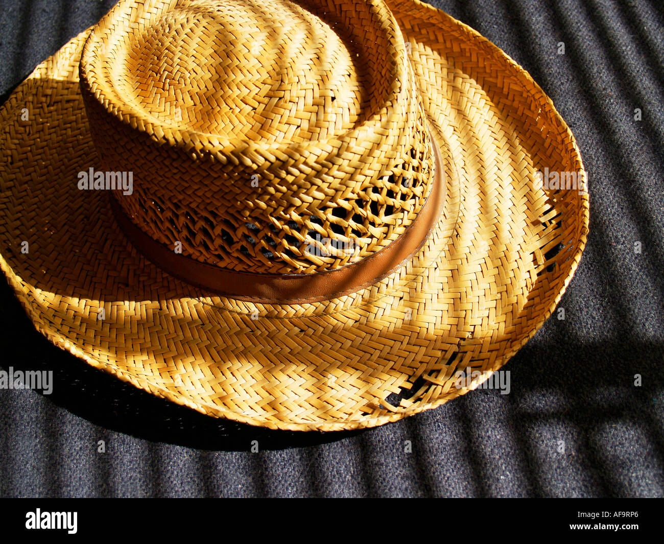 Ancien chapeau de paille usés usure montrant illuminée par la lumière de l'après-midi dans le filtrage à travers les stores Banque D'Images