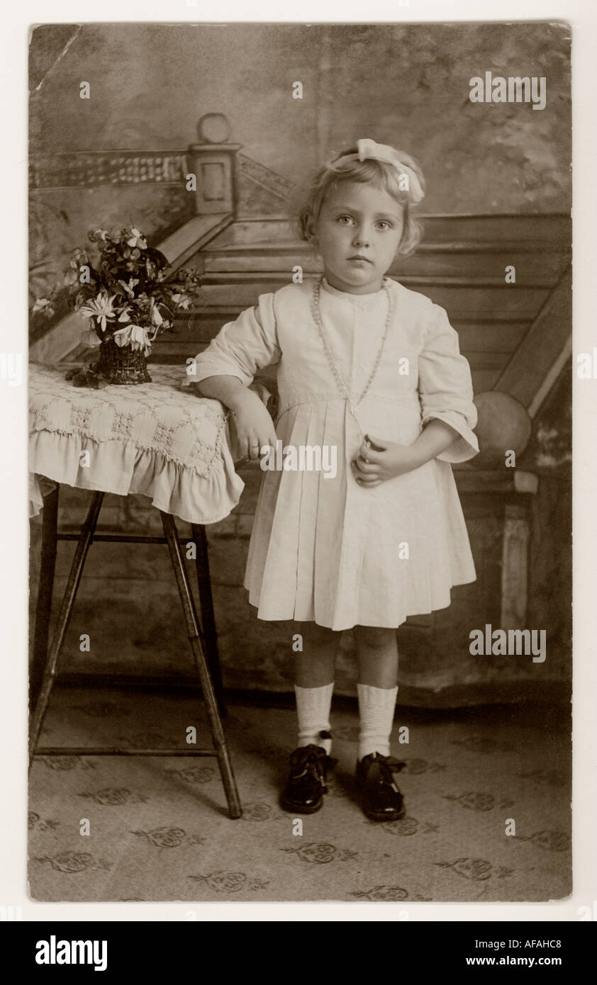 Innocente petite fille douce à la première communion tenue d'un crucifix en 1918 Banque D'Images