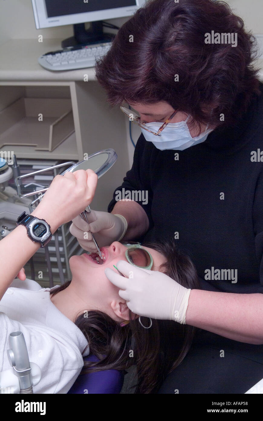 Un jeune garçon utilise un miroir pour examiner son nouvel appareil dentaire Banque D'Images