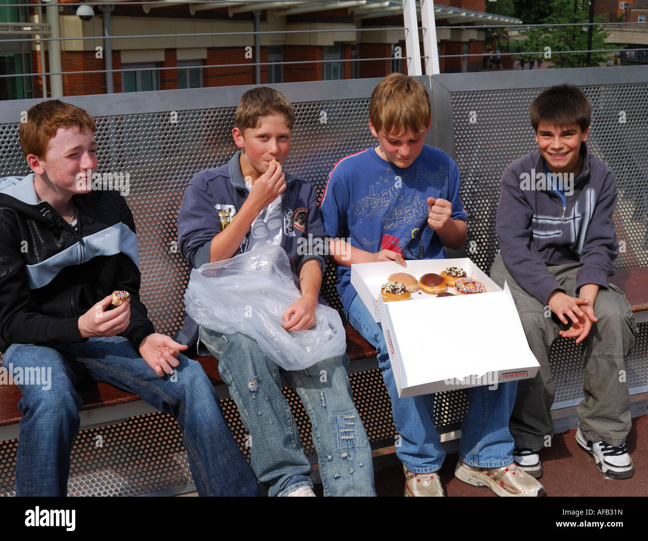Groupe d'adolescents de manger des beignes sur banc, Reading, Berkshire, Angleterre, Royaume-Uni Banque D'Images