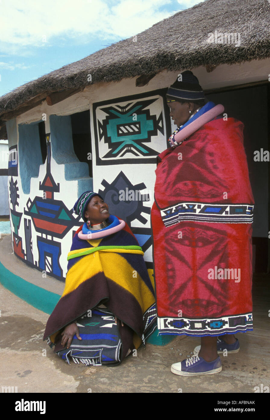 L'Afrique du Sud, Ndebele Mapoch, village près de Pretoria, la femme onversing par chambre avec des peintures murales traditionnelles Banque D'Images