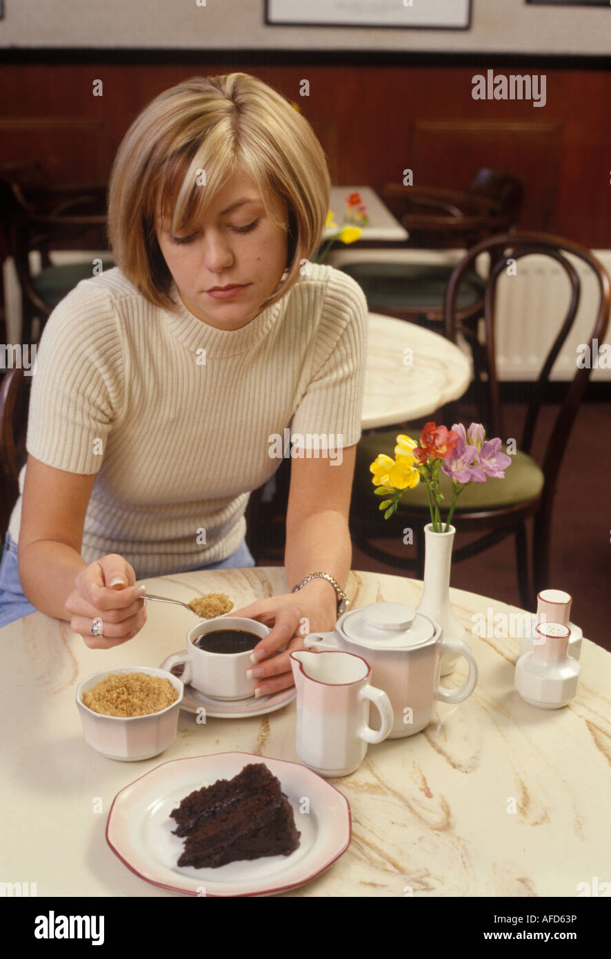 Déprimé woman putting le sucre dans son café Banque D'Images