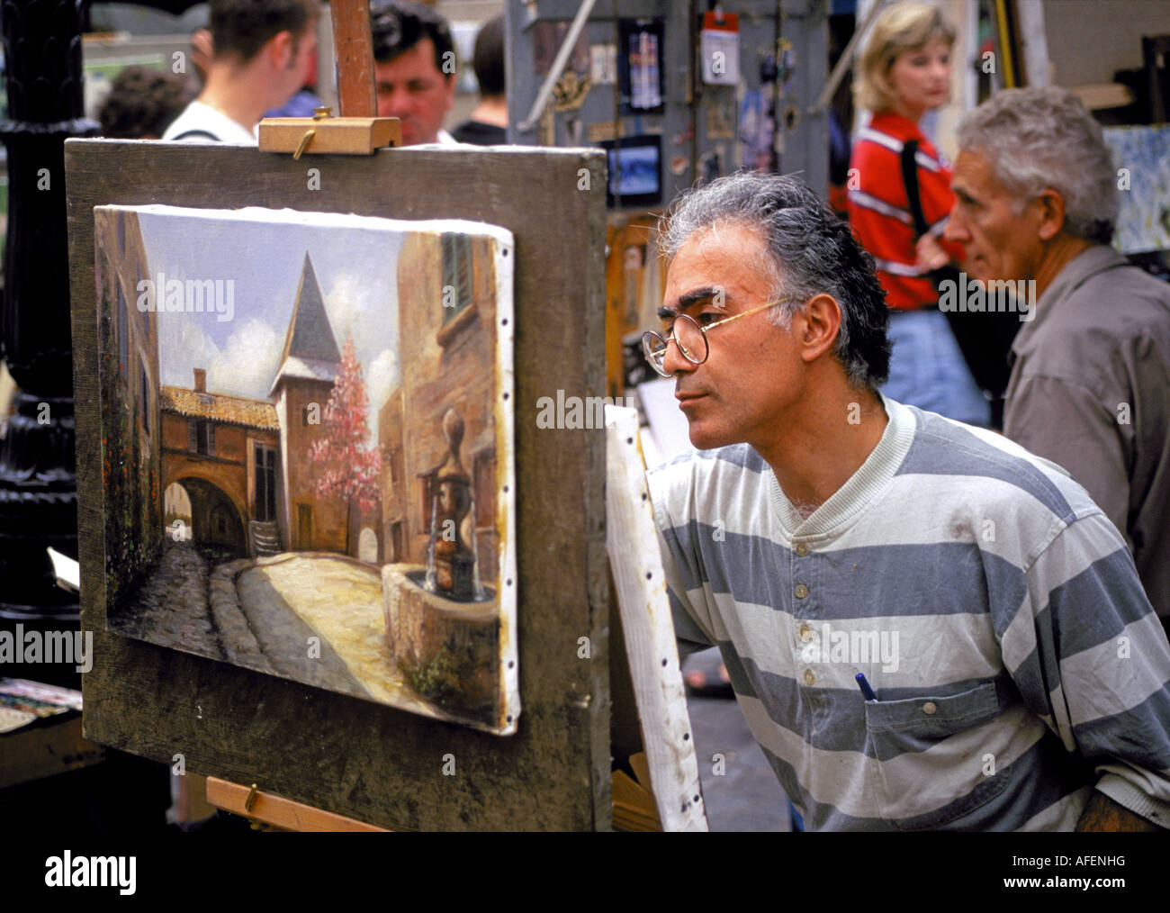 Un peintre travaille au milieu de la foule dans la section de Paris Montmartre dans une petite place sous l'église du Sacré Coeur, Paris, France. Banque D'Images