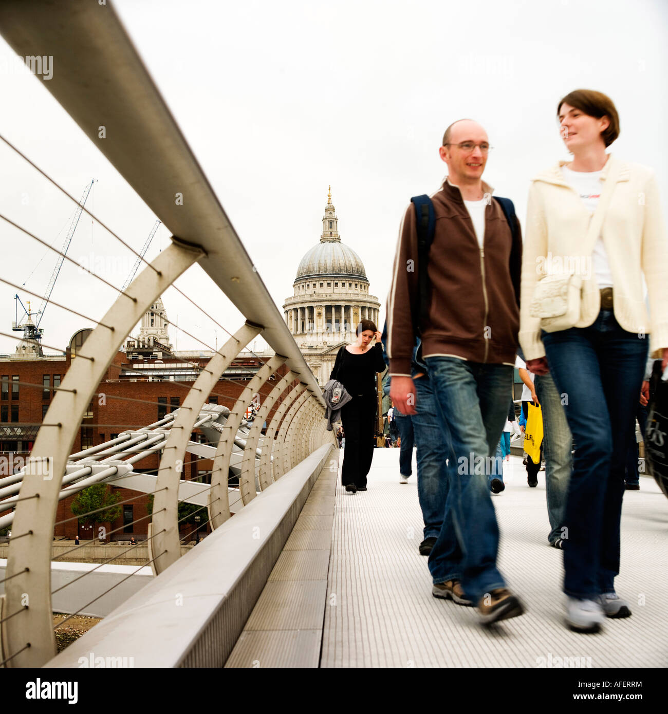 Après-midi d'hiver pâle ciel couple crossing millennium bridge loin de St Pauls vers London Bankside Banque D'Images