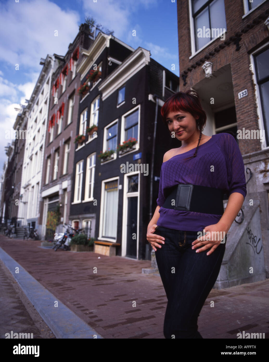 Belle fille néerlandaise pose par côté canal traditionnel de bâtiments dans le centre de Amsterdam. Banque D'Images