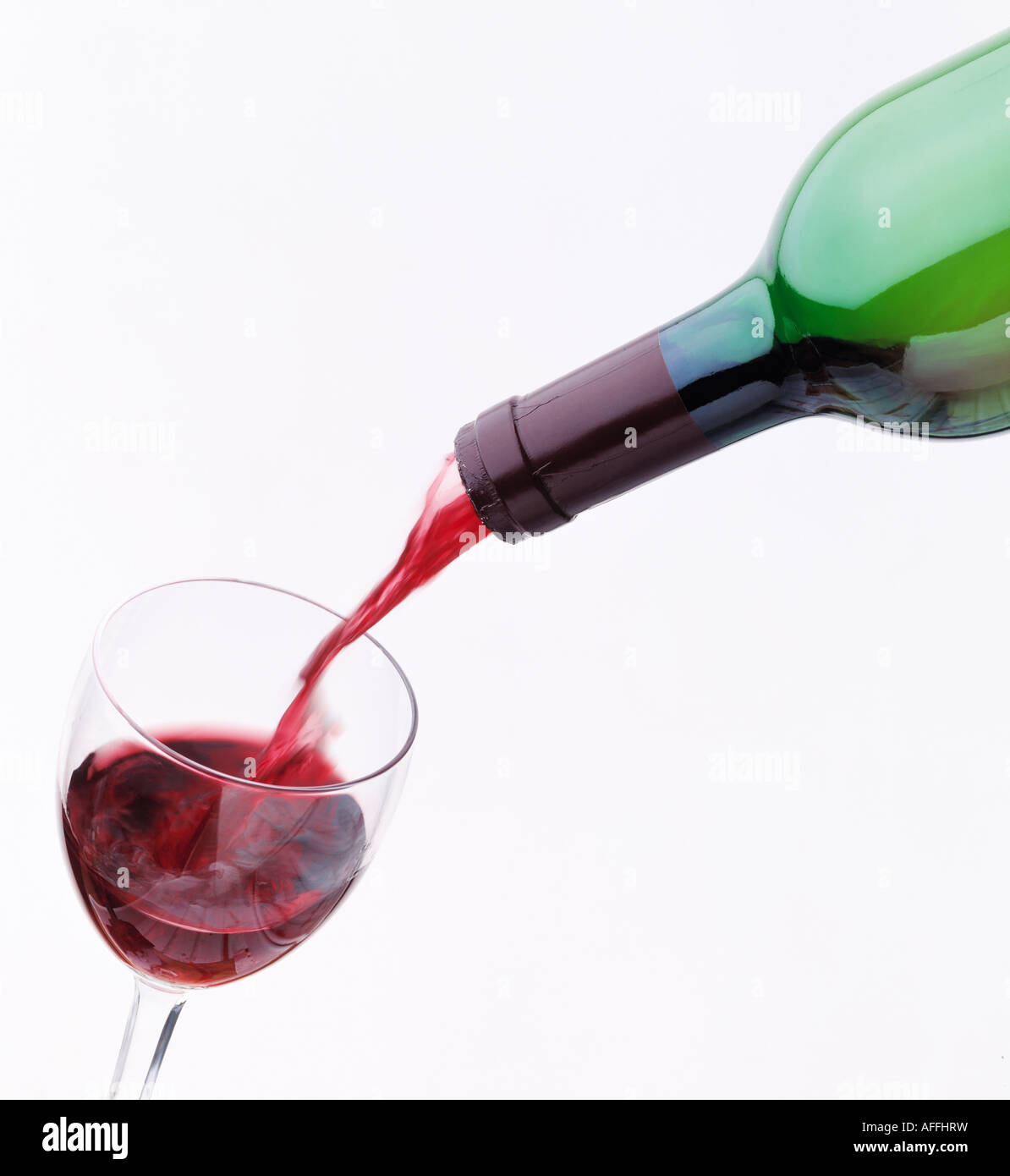 Une bouteille de vin rouge et verser dans un verre de vin sur un fond blanc Banque D'Images